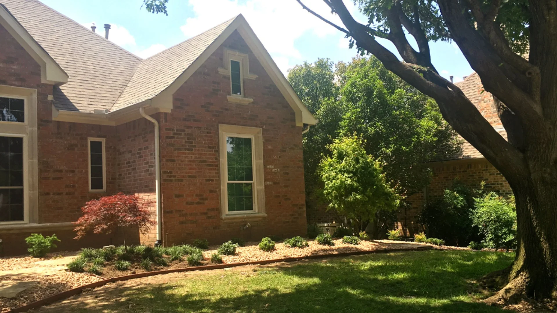 House surrounded by mulched landscape beds with shrubs, grass, and trees in Lucas, TX.