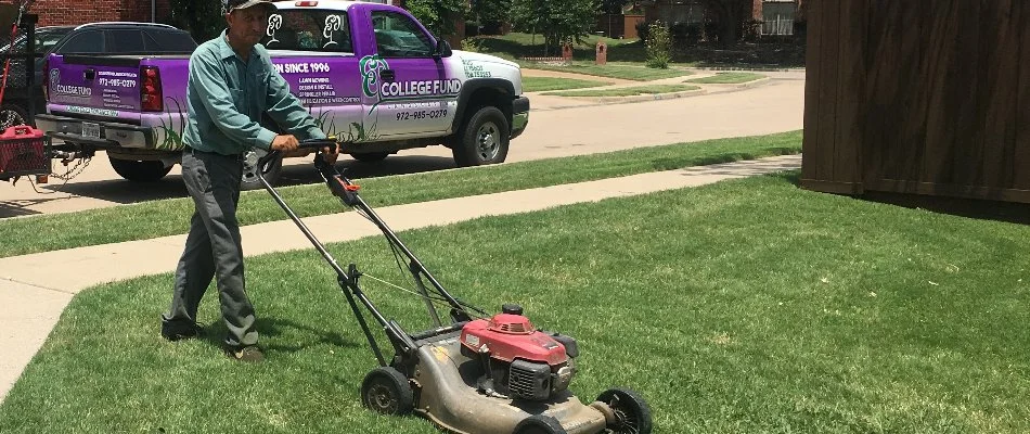 A professional lawn care provider in Plano, TX, mowing a lawn near a purple truck.